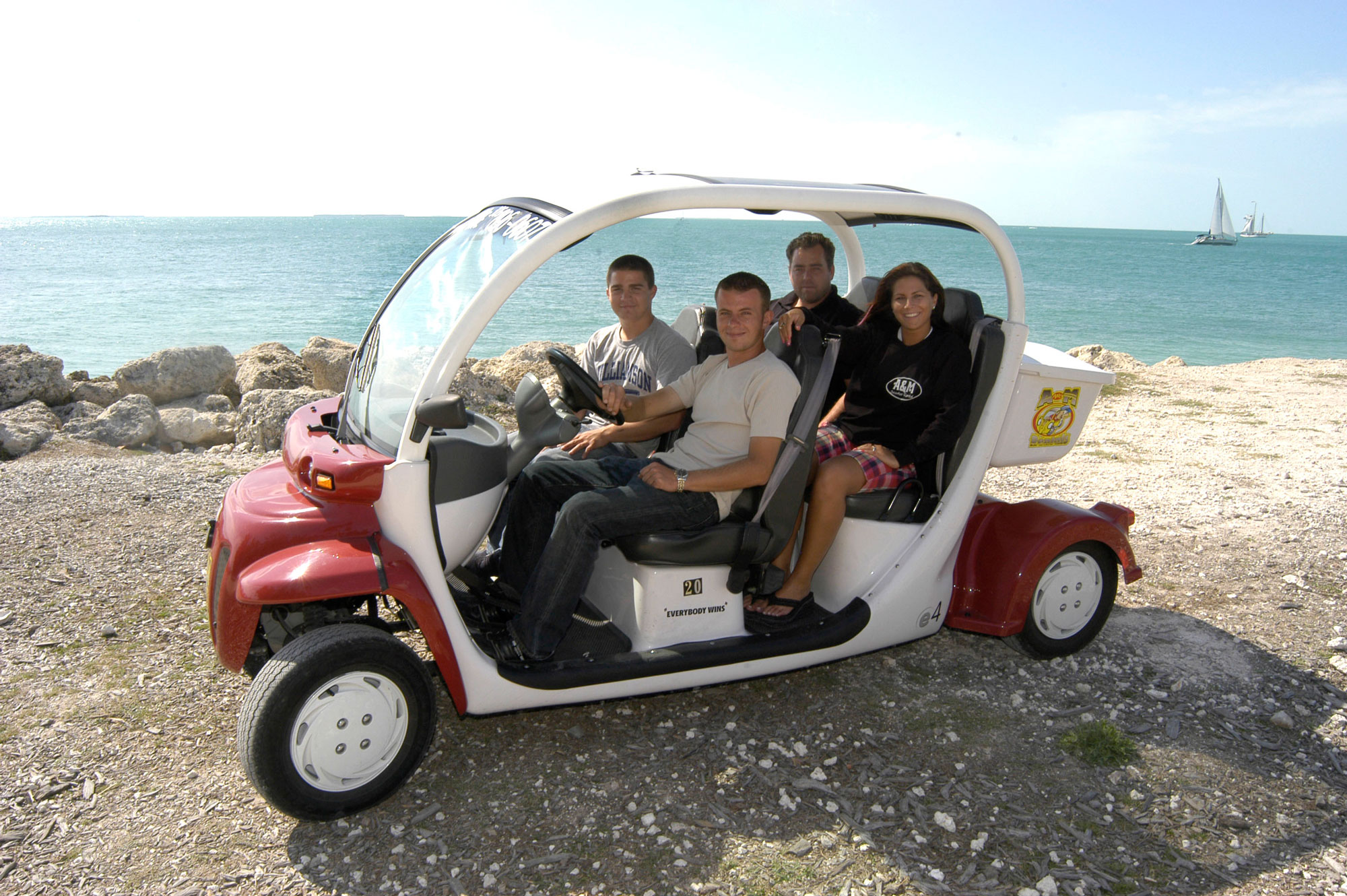 Four tourists in a red and white electric car rental at Fort Zachary National Park by the Ocean in Key West