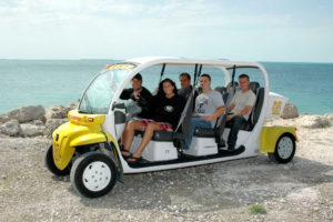 Five tourists in a white and yellow six seats electric car rental at Fort Zachary Taylor by the sea in Key West